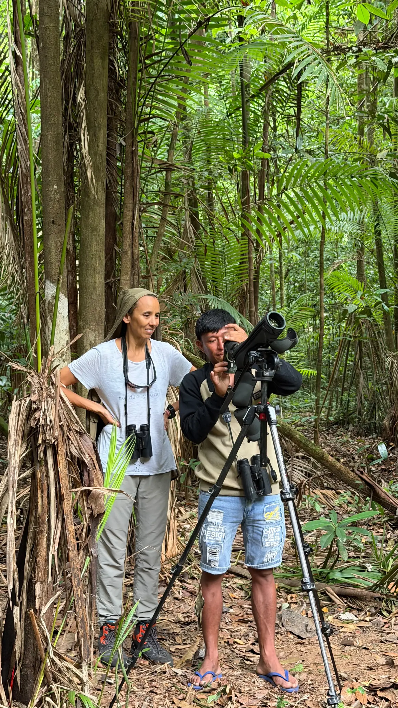 Guide and guest using a spotting scope on a forest trail near Mapari, Guyana